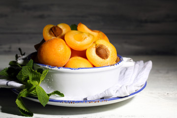 Ripe apricots with green mint leaves in bowl
