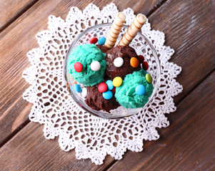 Chocolate ice cream with multicolor candies and wafer rolls in