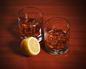 Highball whiskey glass with ice and lemon.