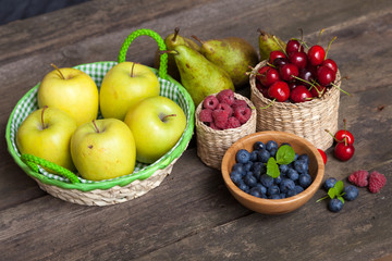 Fresh juicy apples, pears and berries on a wooden table