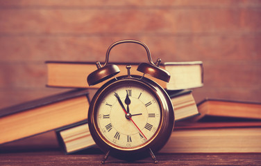 Alarm clock and books on wooden table.