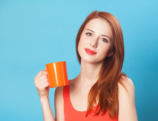 Redhead women with cup on blue background.