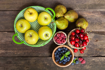 Fresh juicy apples, pears and berries on a wooden table © George Dolgikh