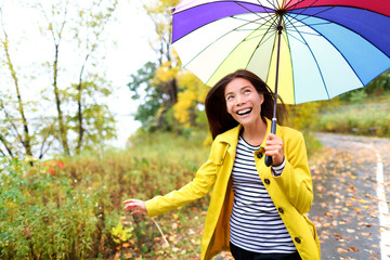Autumn woman happy in rain running with umbrella