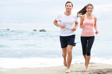 Exercising running couple jogging on beach