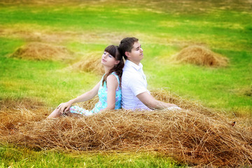 Naklejka na ściany i meble Loving happy couple having fun in a field on a haystack. Summer