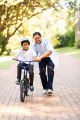 indian father teaching his son to ride a bicycle