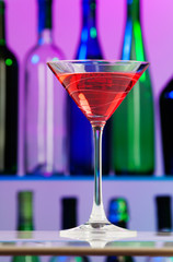 Glass with pink cocktail on centre of bar table
