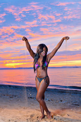 Fototapeta premium Beautiful black African American woman posing on the beach at su