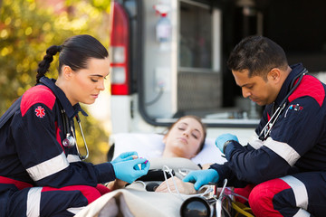 paramedics giving unconscious young woman first aid