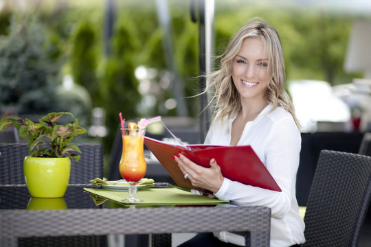 Portrait of young beautiful woman sitting in a cafe outdoor drin
