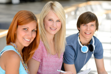 Three smiling student friends looking at camera