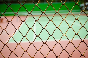 Fototapeta premium Wire fence with tennis court on background