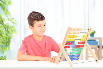 Kid counting with abacus seated on table at home