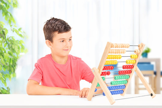 Kid counting with abacus seated on table at home