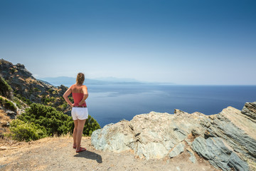 Fototapeta premium Woman looking out over Mediterranean coast from Cap Corse in Cor