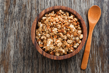 homemade granola in a wooden bowl and spoon, top view - obrazy, fototapety, plakaty
