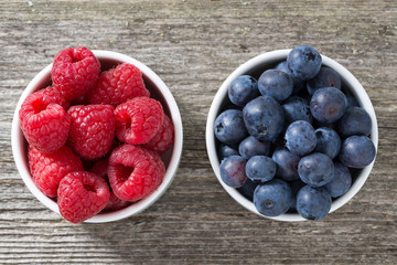 raspberries and blueberries in bowls, top view