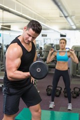 Obraz na płótnie Canvas Muscular man and woman lifting weights