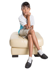 Fototapeta na wymiar Young Asian school girl in uniform sitting on a couch