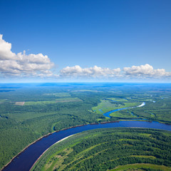Fototapeta na wymiar Forest river under white clouds, top view