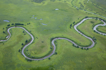aerial view over the small river on the green grassland