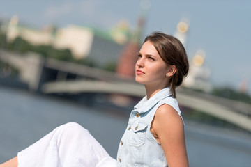 Beautiful girl in white dress sitting on the parapet of the emba