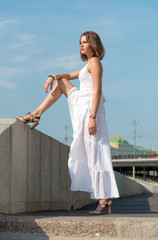 Fototapeta na wymiar Beautiful girl in white dress strolls along the river