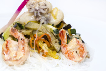 warm salad of noodles and seafood on a white background in the restaurant
