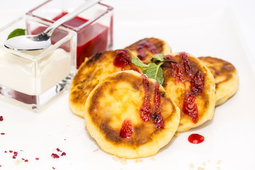 cheesecakes with sour cream and jam on table in restaurant