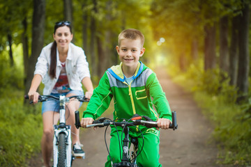 Obraz premium mother and son riding bicycle in the park