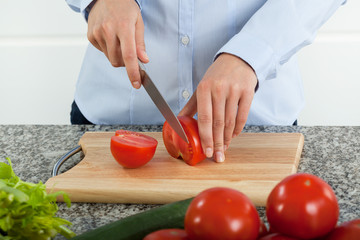 Cutting fresh red tomatoes on cutting board