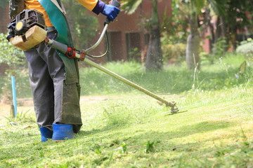 lawn mower worker cutting grass in green field