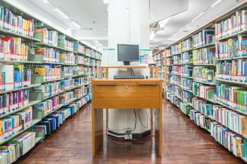 computer in a library with many books and shelves in the backgro