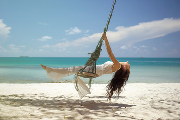 Beautiful woman on a swing on the beach