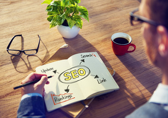 Hipster Writing SEO Concepts on his Note