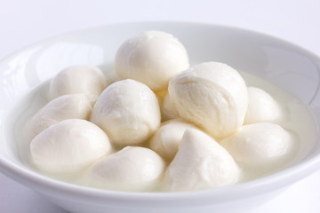 Fototapeta na wymiar Small white mozzarella balls in a white dish with liquid.