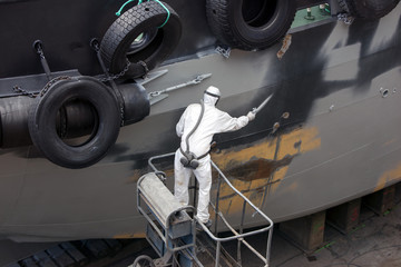 man spray painting hood of ship