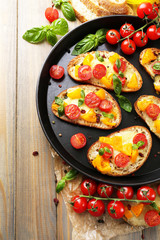 Tasty bruschetta with tomatoes on pan, on old wooden table