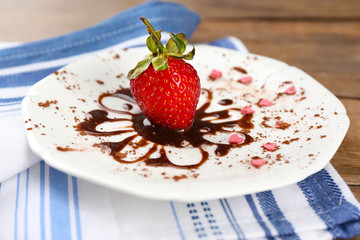 Red ripe strawberry with chocolate on wooden table