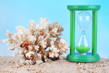 Hourglass in sand on blue sky background