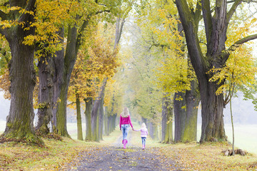 Fototapeta premium mother with her daughter in autumnal alley