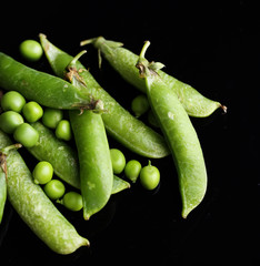 Fresh green peas isolated on black background