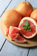 Fototapeta na wymiar Ripe grapefruits on plate on color wooden background