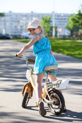 Little girl looking back over her shoulder, sitting on bicycle