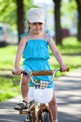 Obraz premium Beautiful girl in blue dress riding bicycle