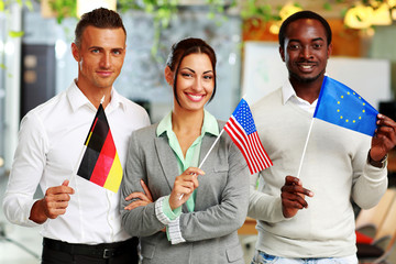 Happy group of businesspeople standing with flags in office