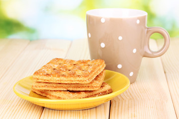 Cup of tea and cookies on wooden table on bright background