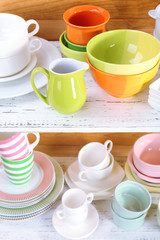 Different tableware on shelf, on wooden background