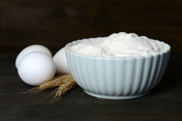 Sifting flour into bowl on table on wooden background